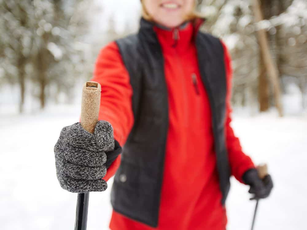 Manos con guantes térmicos mientras caminan por sendero montañoso